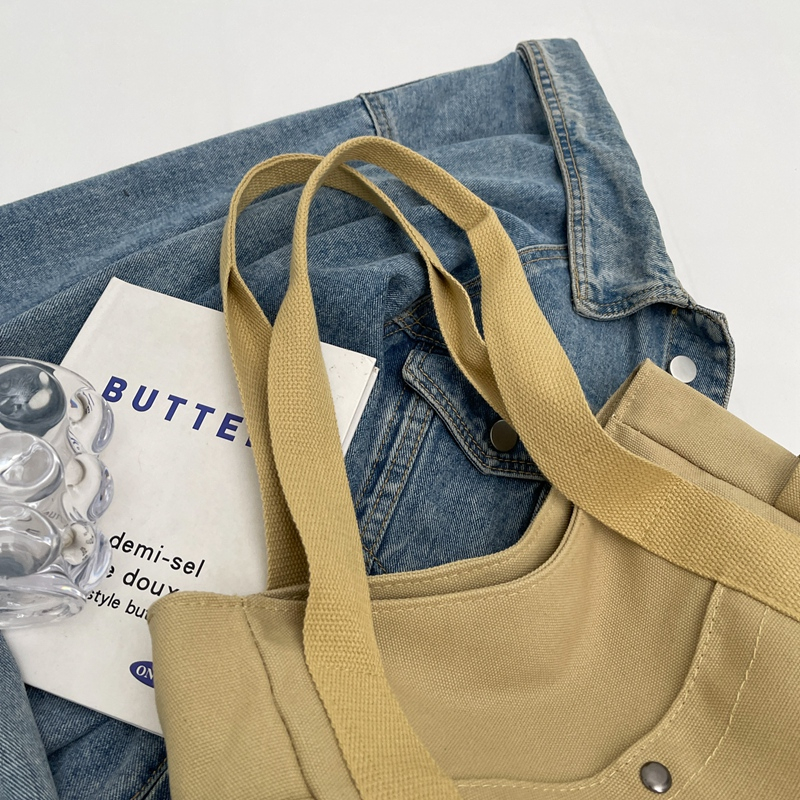 A close-up view of the reinforced shoulder straps and leather buckle details of the thickened canvas tote bag.